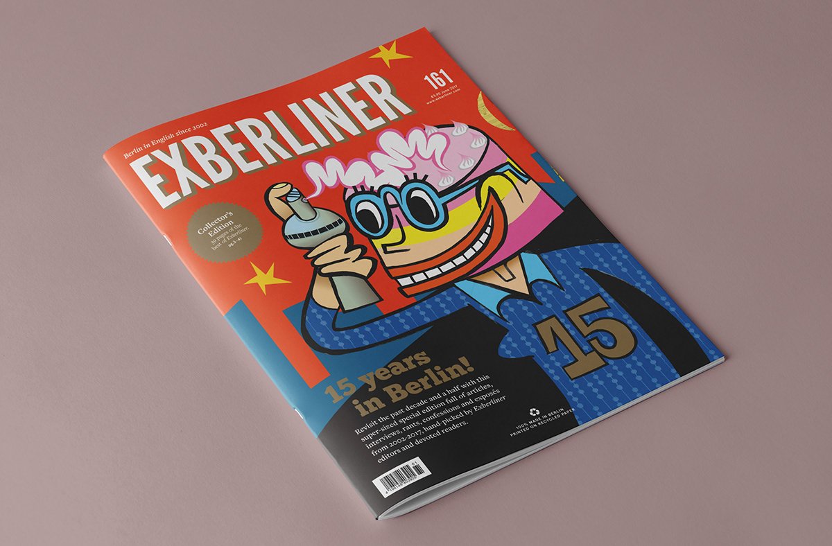 Exberliner #161 — the 15-year special edition, shown lying on a surface; orange cover with a 5-colour illustrated character and metallic gold accents